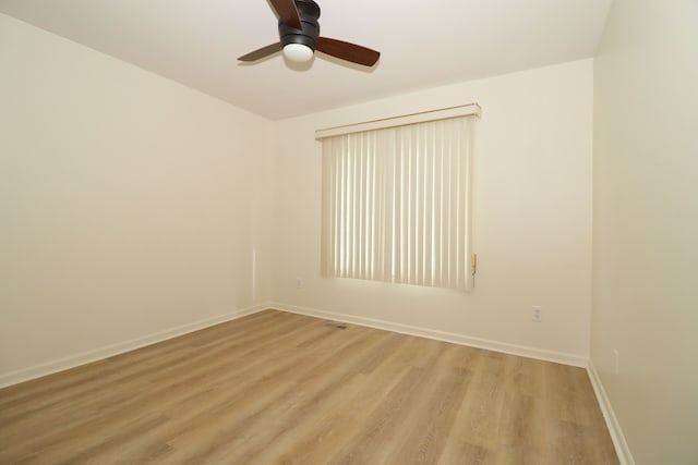 empty room with ceiling fan, light wood-style flooring, and baseboards