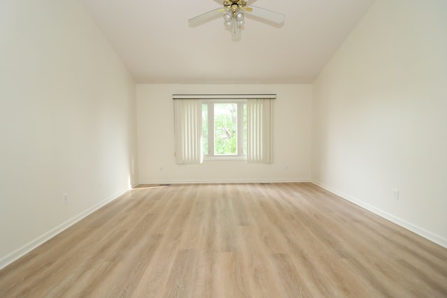 spare room with ceiling fan, baseboards, lofted ceiling, and light wood-style floors