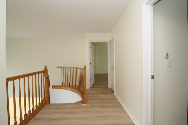 hallway with light wood-type flooring and baseboards