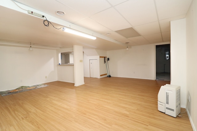 interior space featuring light wood finished floors and a drop ceiling