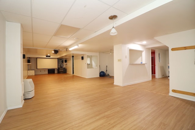 finished below grade area with a paneled ceiling, baseboards, and wood finished floors