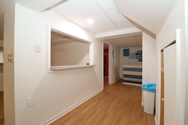 hall featuring a drop ceiling, baseboards, and wood finished floors