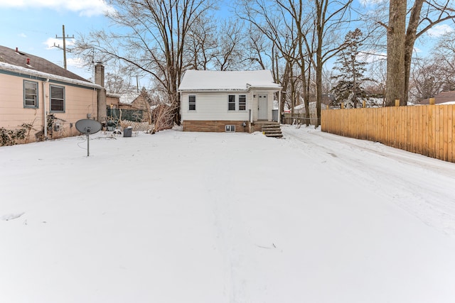 snow covered property with entry steps and fence