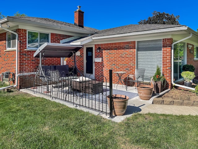 rear view of house with a patio, a chimney, roof with shingles, a yard, and brick siding