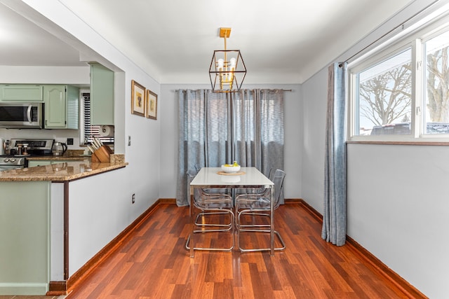 dining room with dark wood-style flooring, a notable chandelier, and baseboards