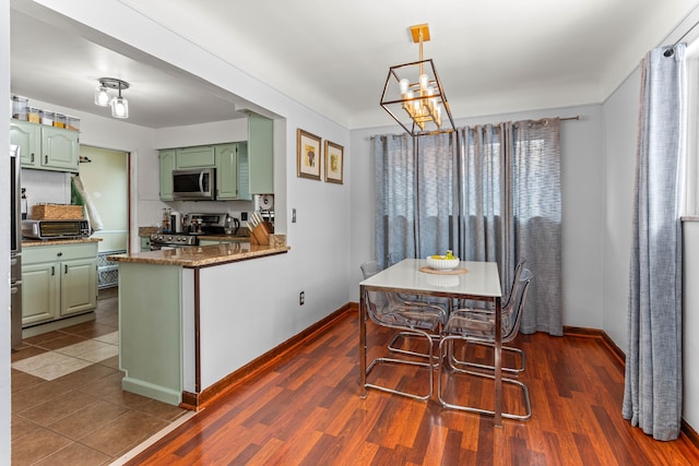 dining area with a notable chandelier, a toaster, dark wood finished floors, and baseboards