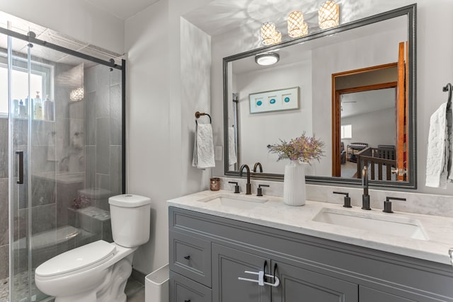 full bathroom with double vanity, a shower stall, toilet, and a sink