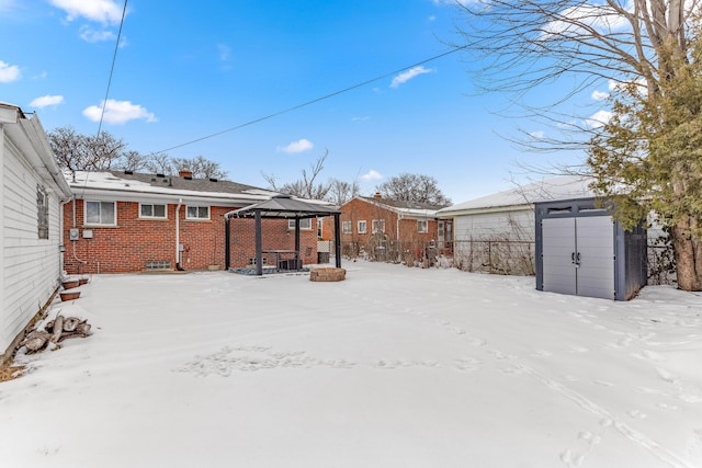 snowy yard with a storage unit, an outbuilding, and a gazebo