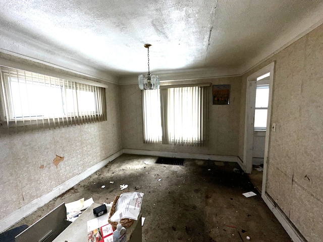 unfurnished dining area featuring baseboards, a chandelier, and a textured ceiling