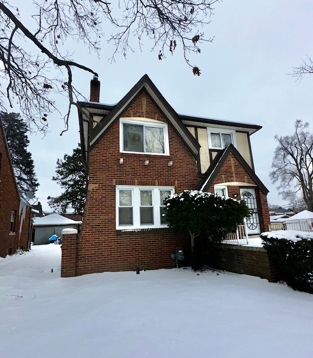 view of front of house with a chimney and brick siding