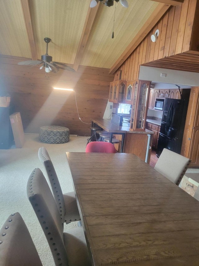 dining room featuring wooden ceiling, carpet floors, wooden walls, a ceiling fan, and vaulted ceiling with beams