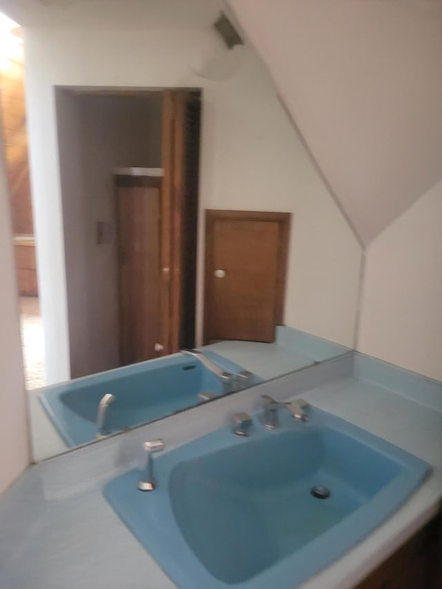 bathroom featuring lofted ceiling and a sink