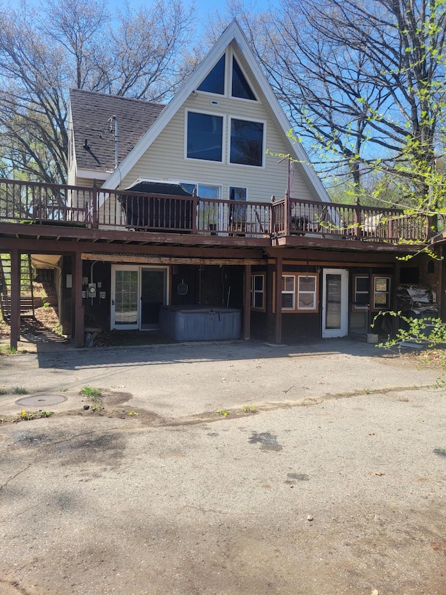 rear view of house featuring a deck and roof with shingles