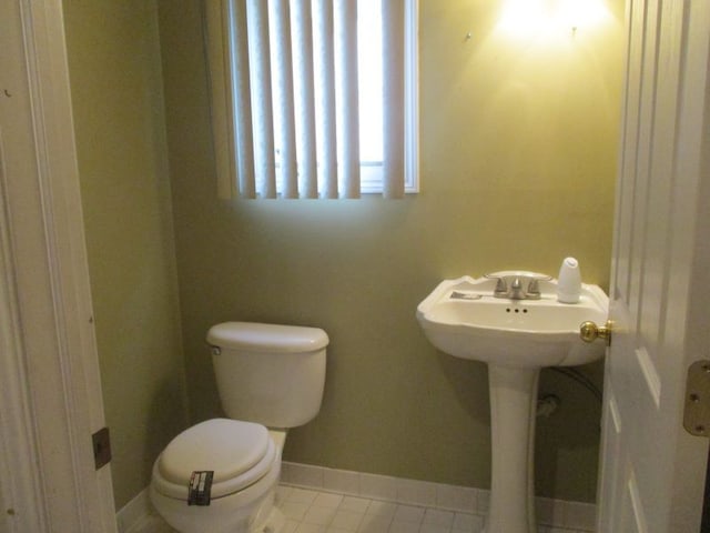 half bathroom featuring tile patterned floors, toilet, and baseboards