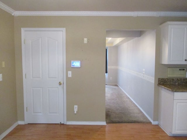 hall featuring ornamental molding, light wood finished floors, and baseboards