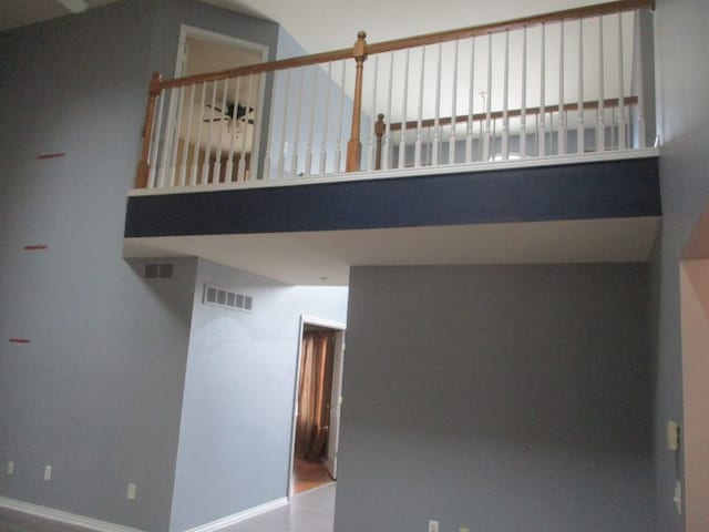 interior space with visible vents, a towering ceiling, and baseboards