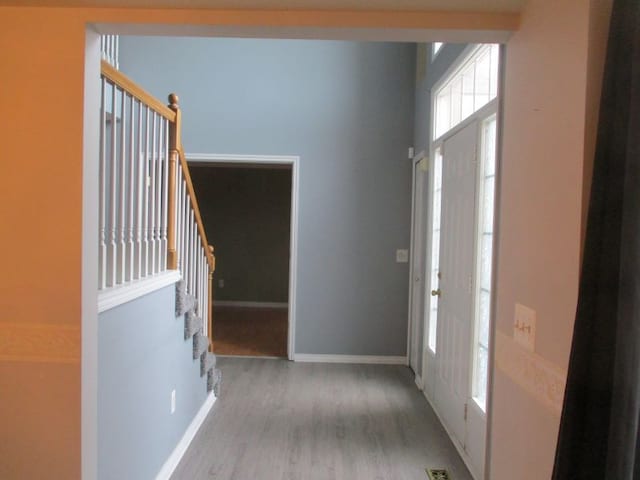 foyer entrance featuring stairway, wood finished floors, and baseboards