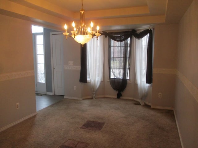 interior space featuring a notable chandelier, plenty of natural light, a raised ceiling, and carpet flooring