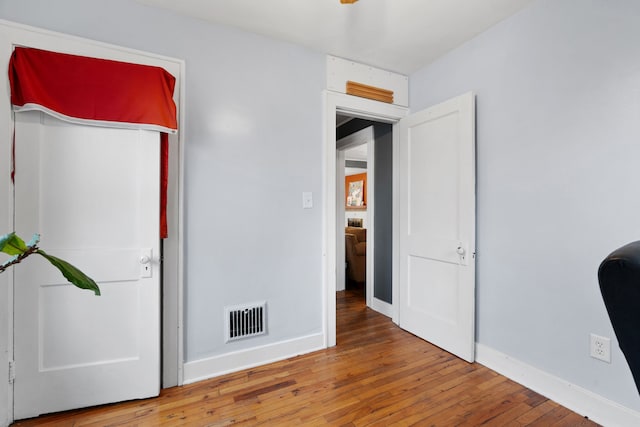 unfurnished bedroom featuring wood-type flooring, visible vents, and baseboards