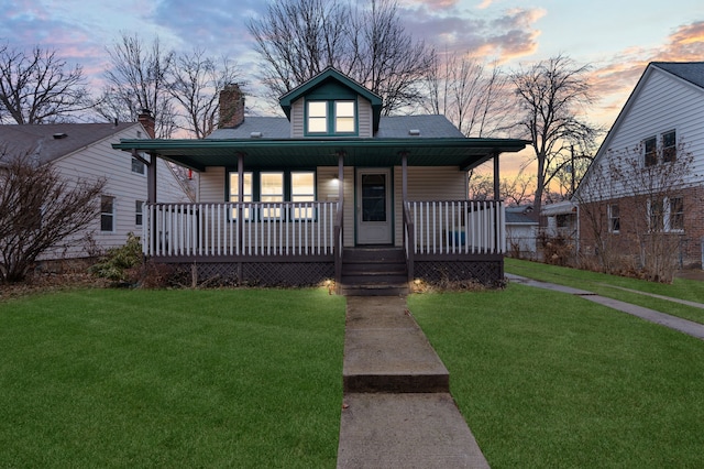 bungalow-style house with a yard, a porch, and a chimney