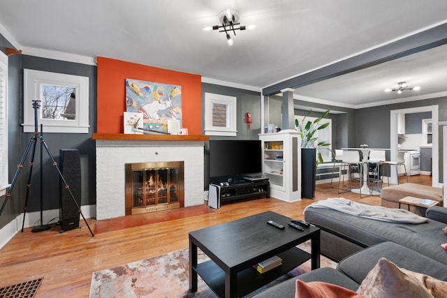 living room with baseboards, a fireplace, wood finished floors, and crown molding