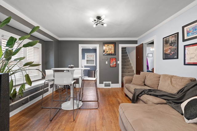 living area with baseboards, visible vents, stairway, ornamental molding, and wood finished floors