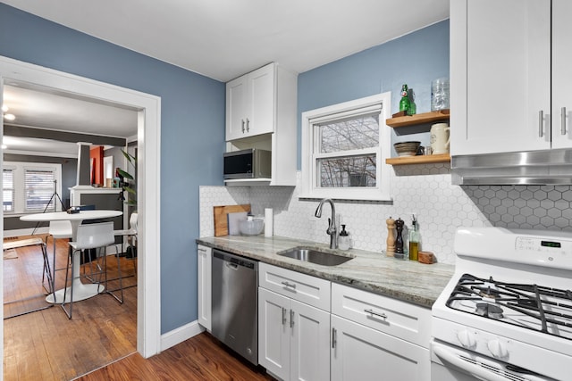 kitchen with dark wood finished floors, stainless steel appliances, white cabinets, a sink, and extractor fan