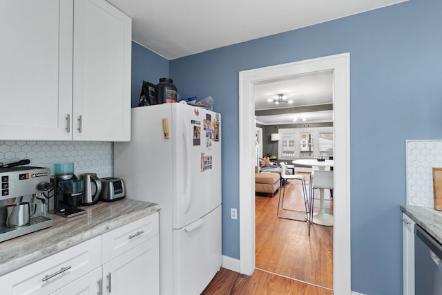 kitchen featuring tasteful backsplash, wood finished floors, freestanding refrigerator, and white cabinets