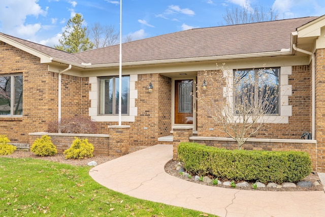 property entrance featuring brick siding and roof with shingles