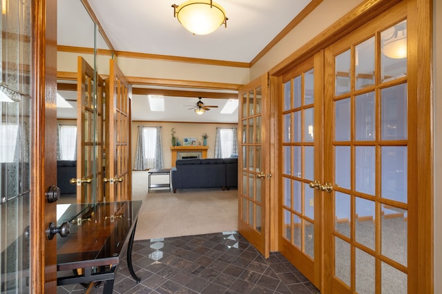 interior space featuring a ceiling fan, french doors, a fireplace, dark colored carpet, and ornamental molding