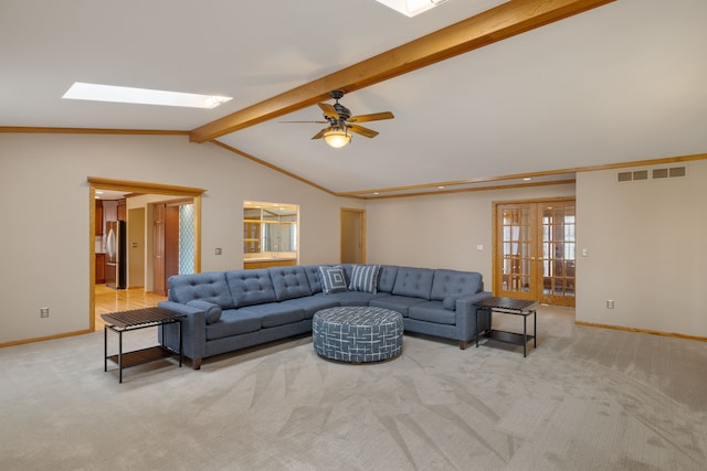 carpeted living area featuring baseboards, ceiling fan, vaulted ceiling with skylight, and visible vents