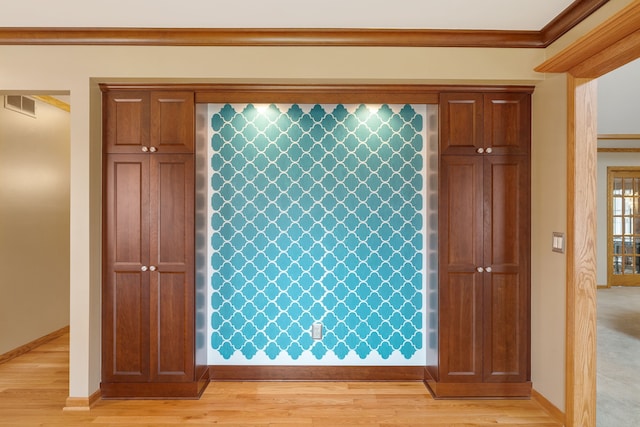 interior space featuring baseboards, ornamental molding, wood finished floors, and visible vents