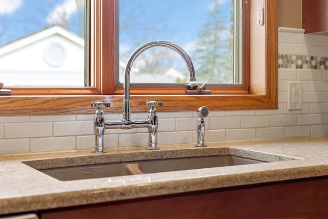 details with a sink, decorative backsplash, and light stone countertops