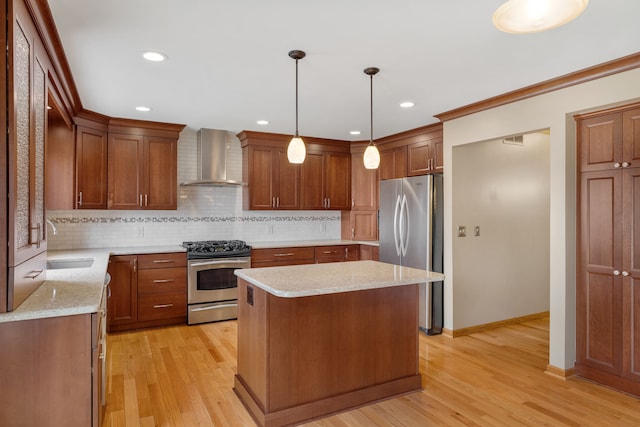 kitchen with appliances with stainless steel finishes, a sink, wall chimney exhaust hood, tasteful backsplash, and a kitchen island