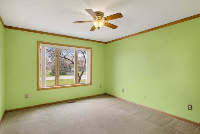 spare room featuring a ceiling fan, visible vents, crown molding, baseboards, and light carpet