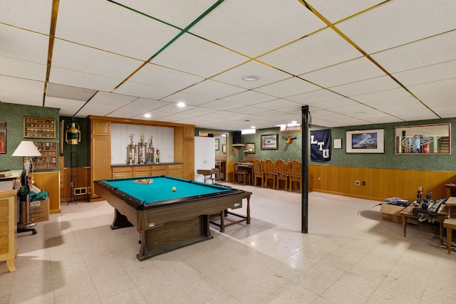 rec room featuring wooden walls, wainscoting, pool table, and a drop ceiling