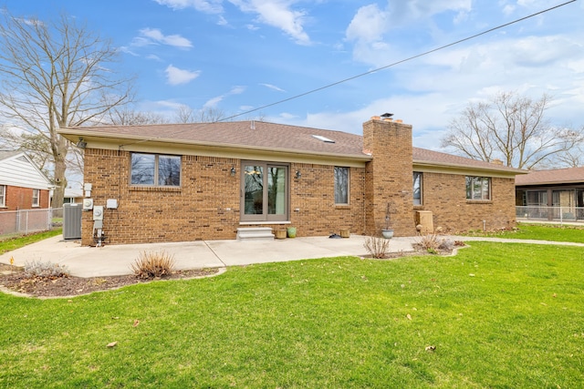 rear view of property with brick siding, central AC unit, a chimney, a patio area, and a yard