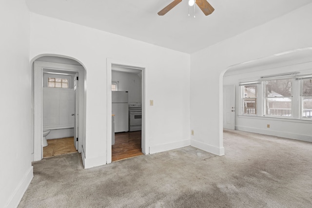 unfurnished room with a wealth of natural light, carpet, and arched walkways