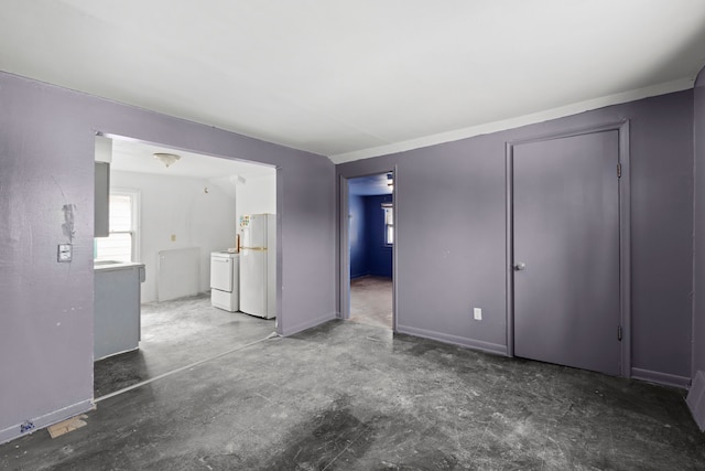 interior space featuring baseboards, concrete floors, and washing machine and clothes dryer