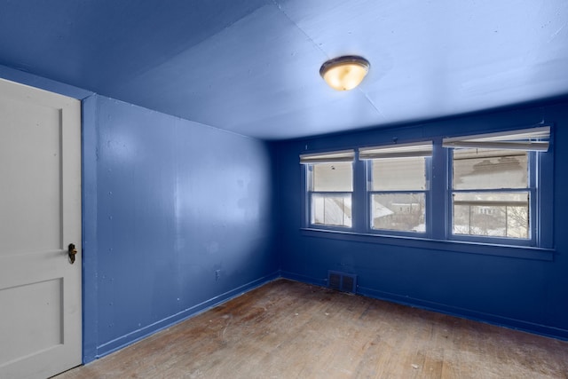 empty room featuring a healthy amount of sunlight, visible vents, and hardwood / wood-style floors