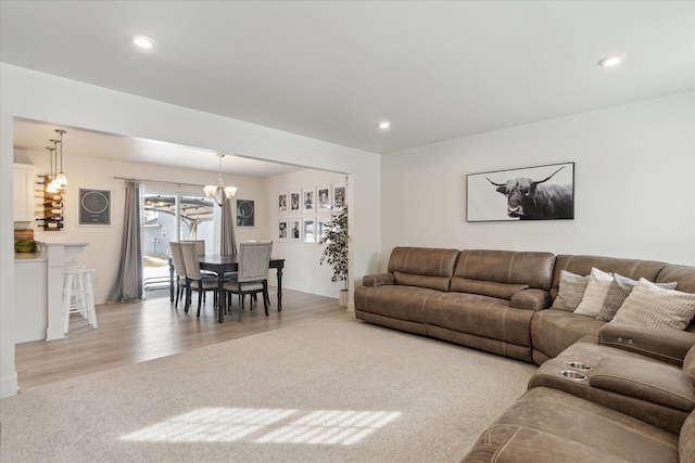 carpeted living room with a notable chandelier, wood finished floors, and recessed lighting