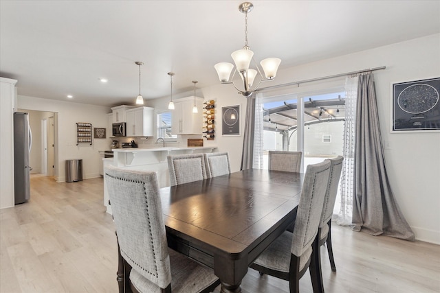 dining space with baseboards, recessed lighting, light wood-type flooring, and an inviting chandelier