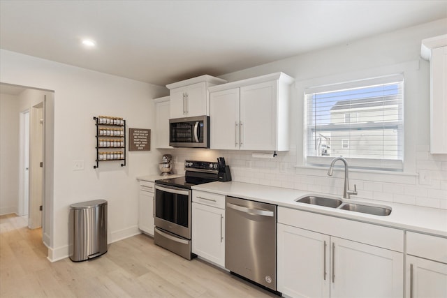 kitchen featuring white cabinets, stainless steel appliances, a sink, and light countertops