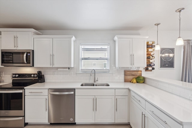 kitchen featuring white cabinets, appliances with stainless steel finishes, light countertops, and a sink