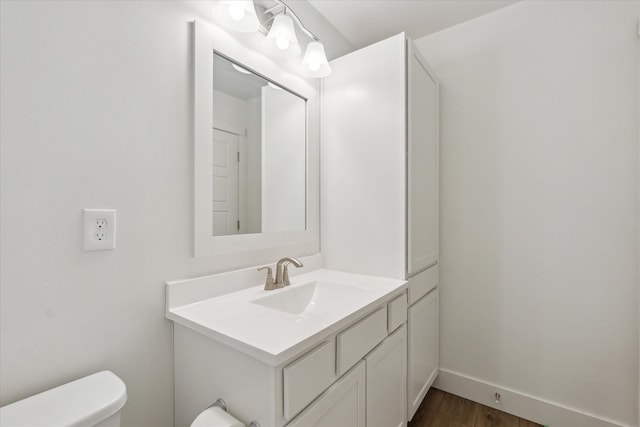 bathroom featuring wood finished floors, vanity, toilet, and baseboards