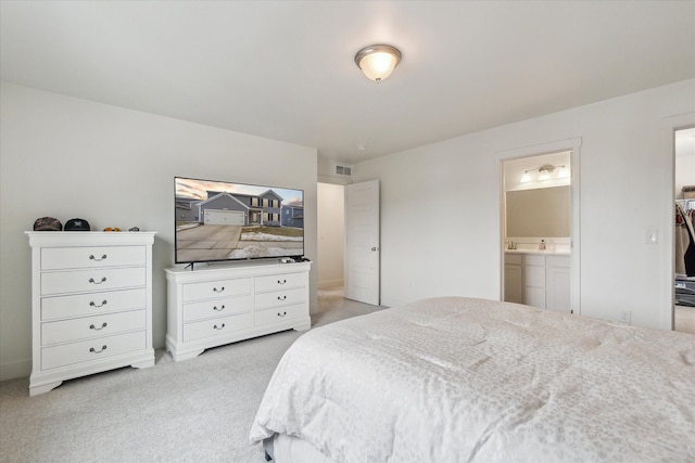 bedroom with light colored carpet, visible vents, and ensuite bathroom