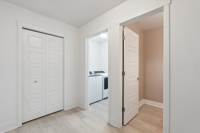 hallway with independent washer and dryer, light wood-style flooring, and baseboards