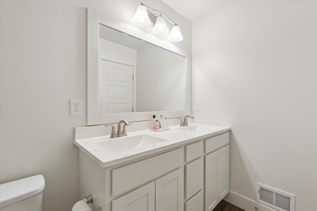 bathroom with visible vents, a sink, toilet, and double vanity