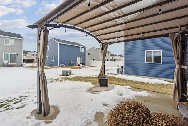 snow covered patio featuring fence, a residential view, and a pergola