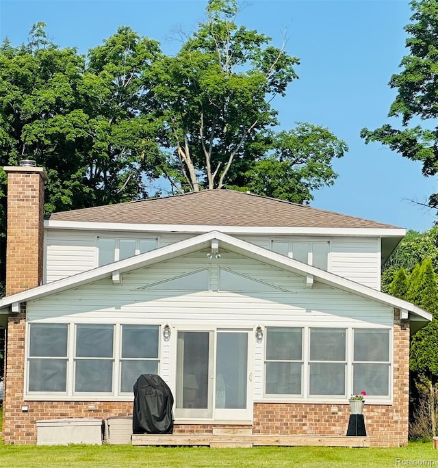 11375 SW Torch Lake Dr, Rapid City, MI 49676 - back of house featuring a sunroom, brick siding, and a chimney